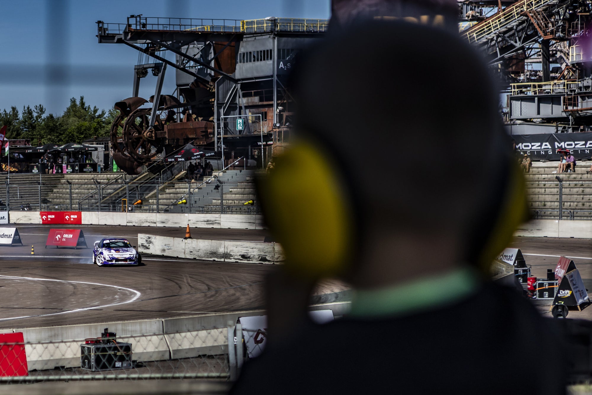 Drift car mid-corner at Drift Masters Ferropolis, watched from the grandstand